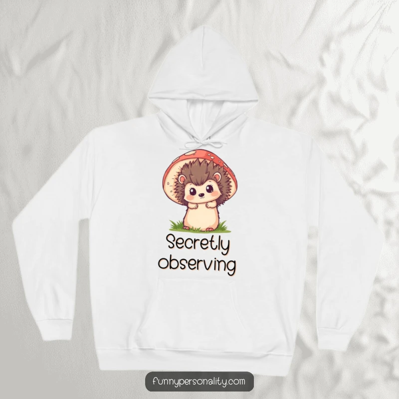 Funny hoodie depicting a curious hedgehog peeking from behind a large, detailed mushroom, offering cozy woodland enchantment.